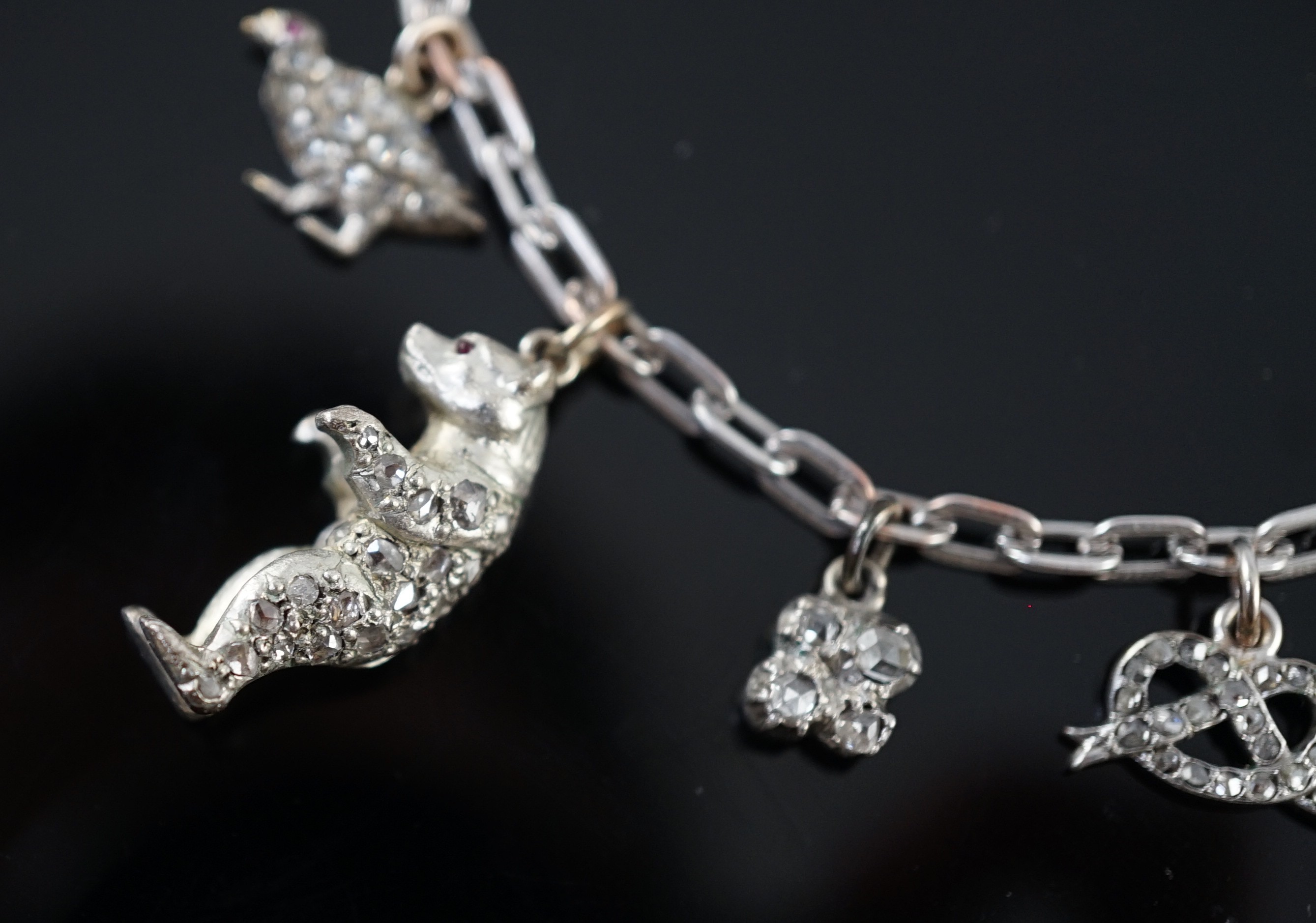 A 9ct white gold charm bracelet, with French platinum and diamond set clasp and hung with nine assorted charms, eight set with diamonds